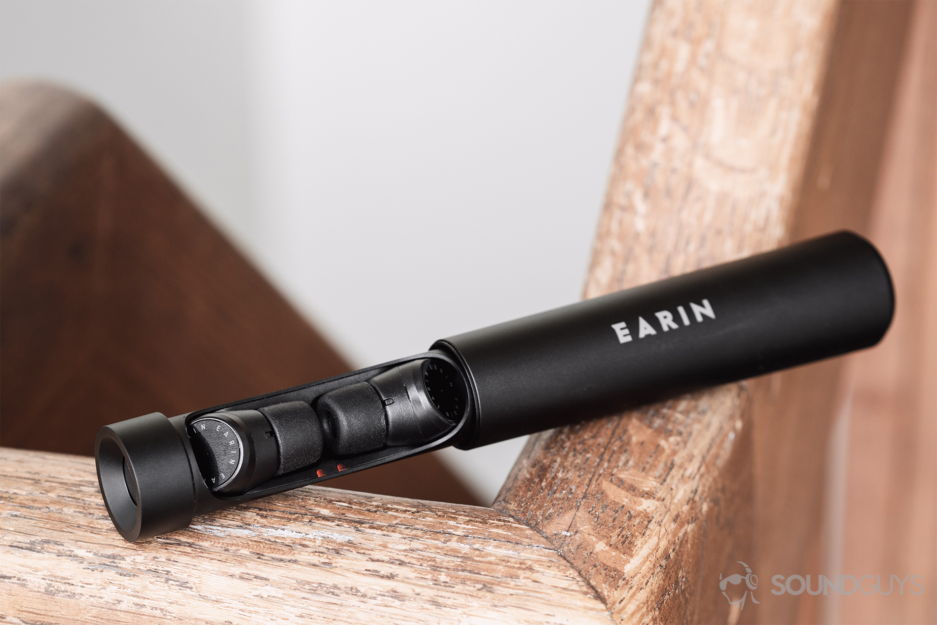 Earin M-2 review: The charging capsule is open, revealing the Earin M-2 true wireless earbuds resting on a railing.
