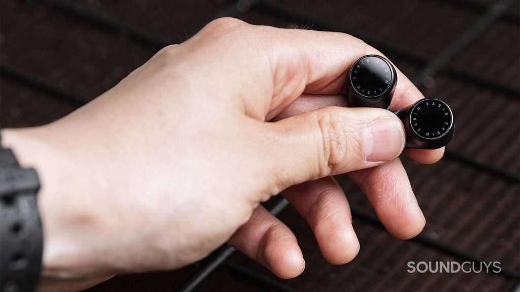 The Earin M-2 earbuds are in the hand, showing off the touch control panels.