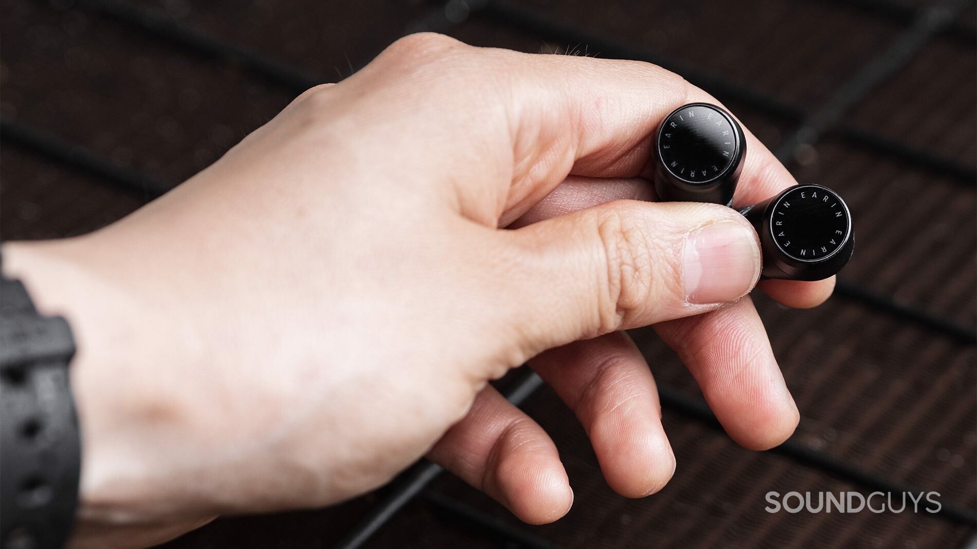 The Earin M-2 earbuds are in the hand, showing off the touch control panels.