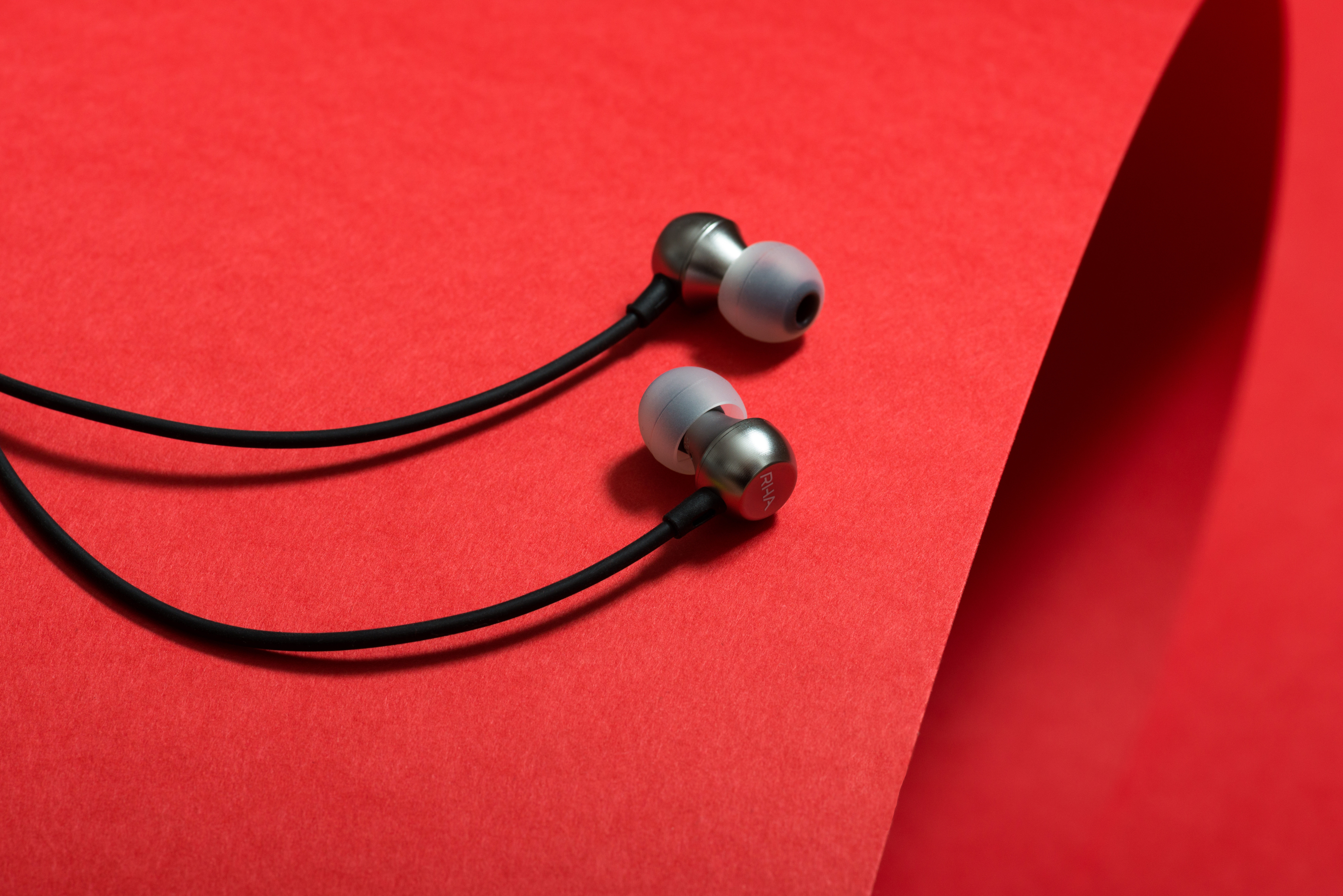 RHA MA390 Wireless announcement: A close-up of the earbuds on a red background.
