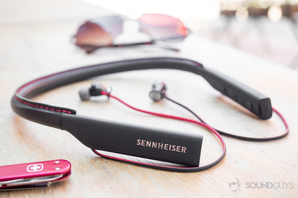 neckband earbuds Sennheiser HD1 In-Ear Wireless: The earbuds on a wood table with sunglasses in the background and a Swiss Army knife in the foreground.