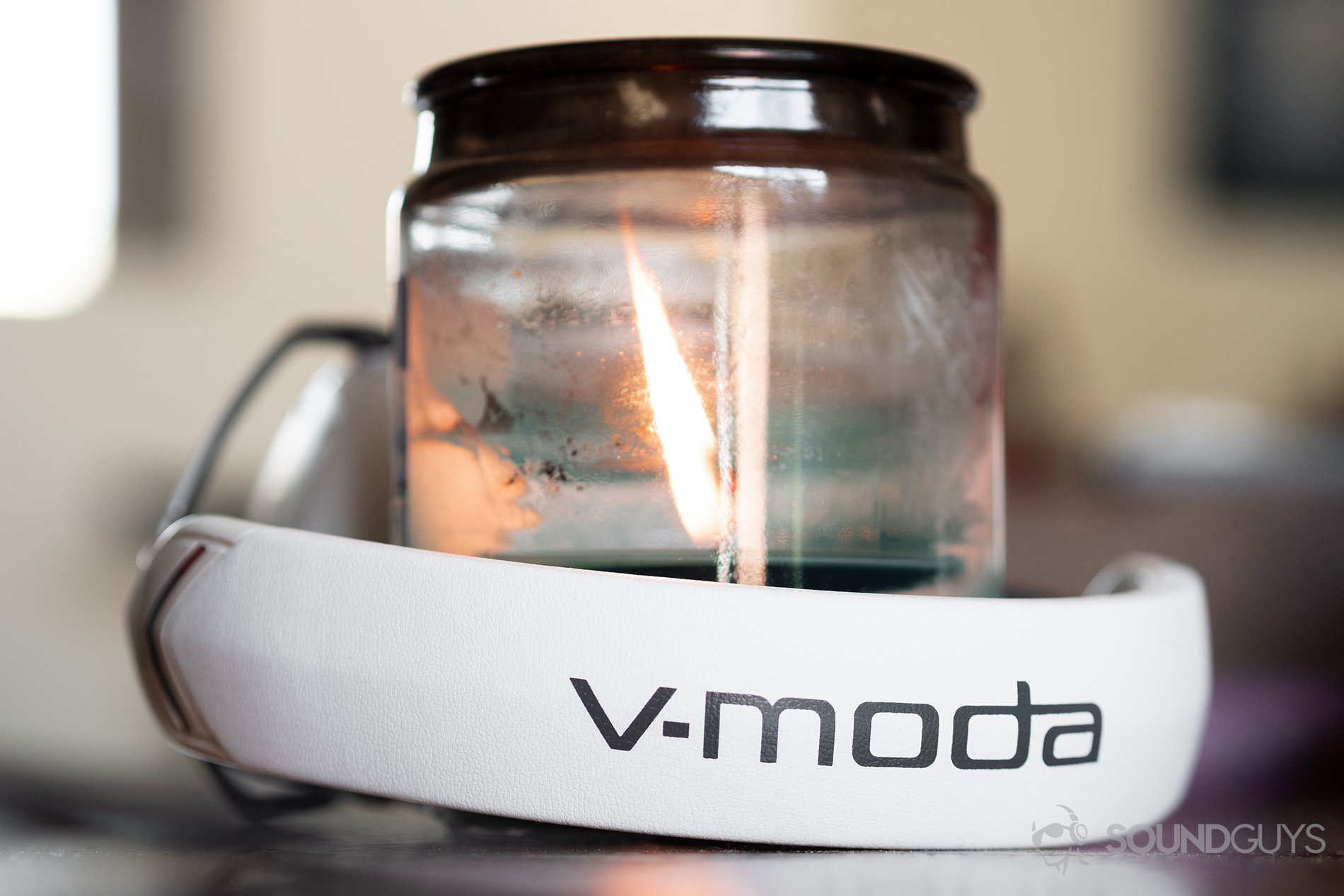 V-Moda_Crossfade 2 Codex-1 The V-Moda Crossfade 2 Codex headphones wrapped around a large candle/holder. The headband is facing the camera and reads "V-Moda."