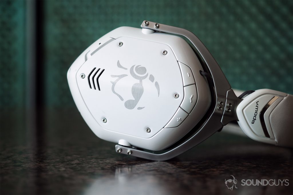The V-Moda Crossfade 2 Codex right earcup laying horizontally on a table with a green background.