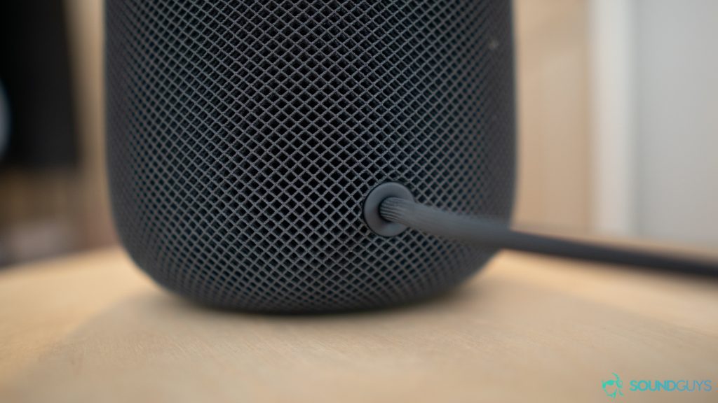The power supply cable of the Apple Homepod which is on a wooden stool. 