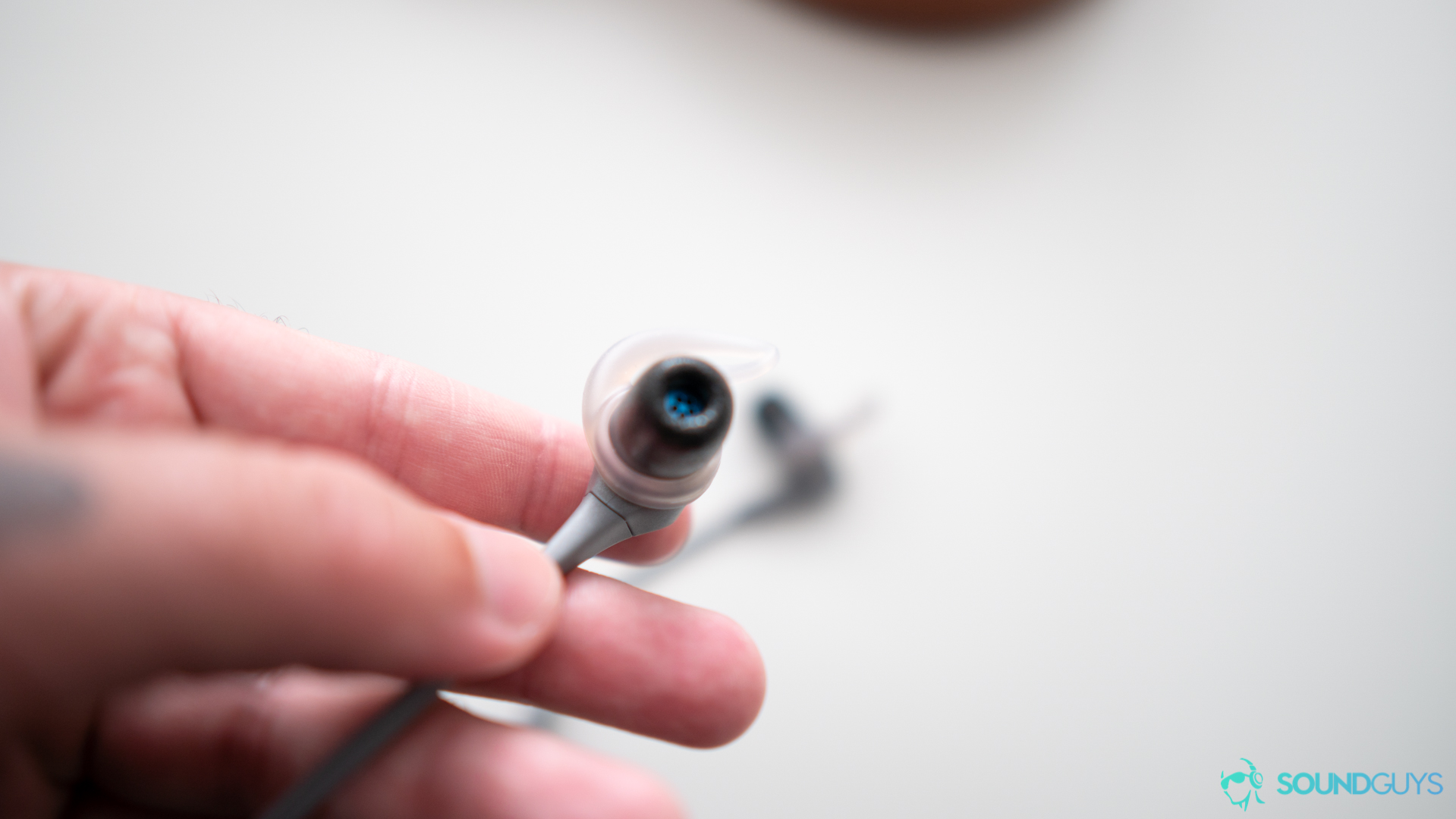 Man holding single Jaybird X4 earbud with focus on the nozzle. 