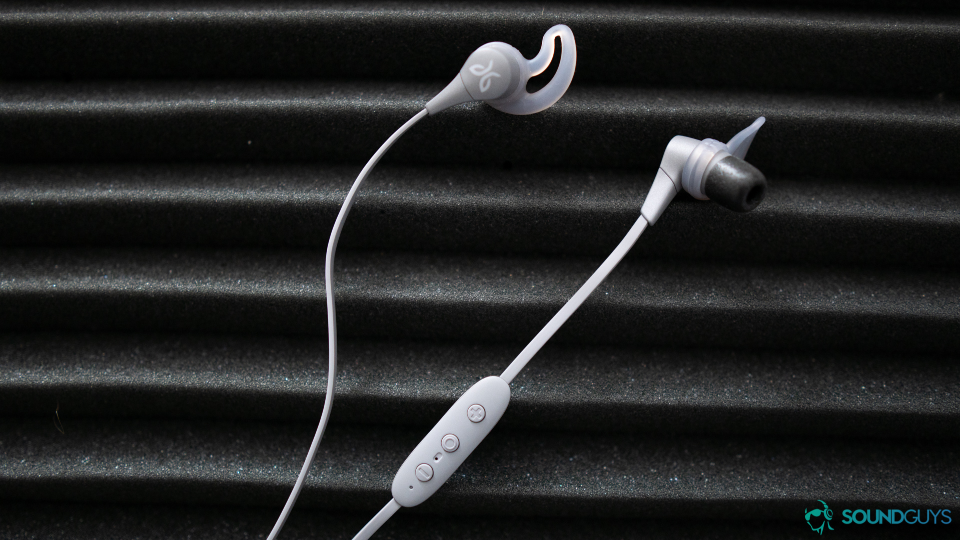 The gray version of the Jaybird X4 earbuds on a gray piece of soundproof foam. 