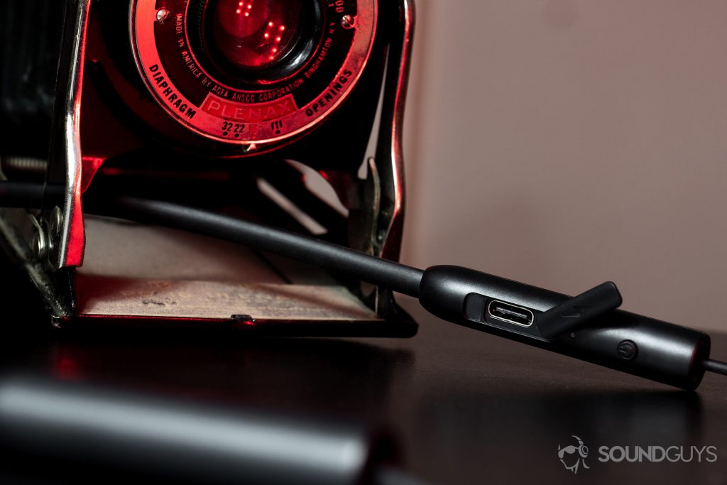 RHA MA390 Wireless: An image focused on the USB-C port on the right side of the neckband with a Plenax camera in the background.