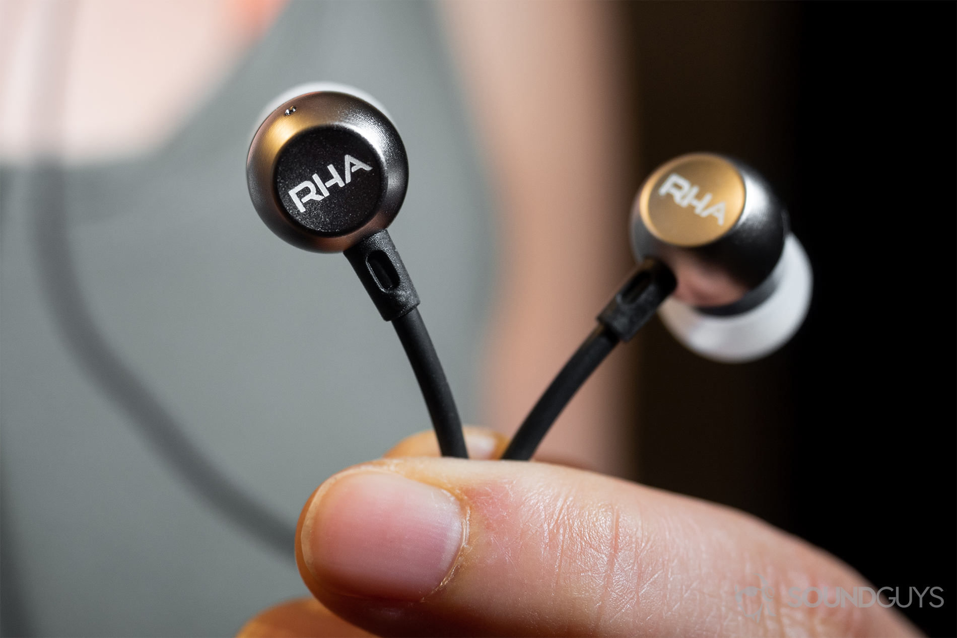 RHA MA390 Wireless: The earbuds in the hand set in front of Lily's torso.