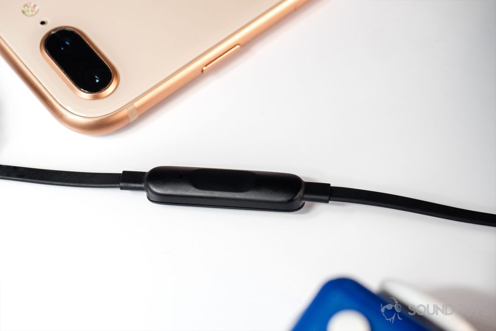 BeatsX review: An angled, top-down image of the in-line mic resting horizontally (middle) across the image. The top portion of the image features an iPhone 8 Plus in rose gold.