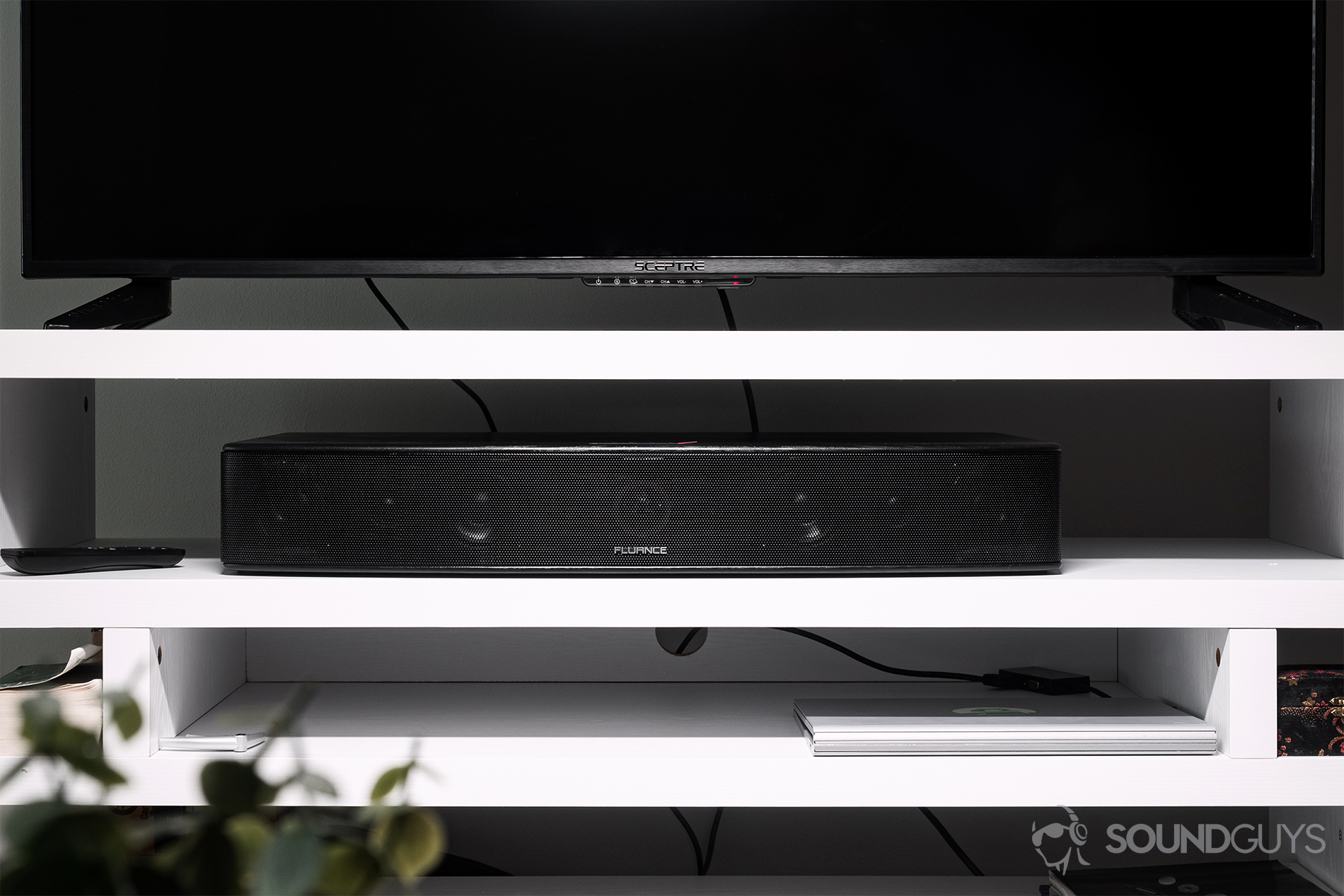 Fluance AB40 review: The soundbar resting in a TV stand beneath a 55&quot; TV.