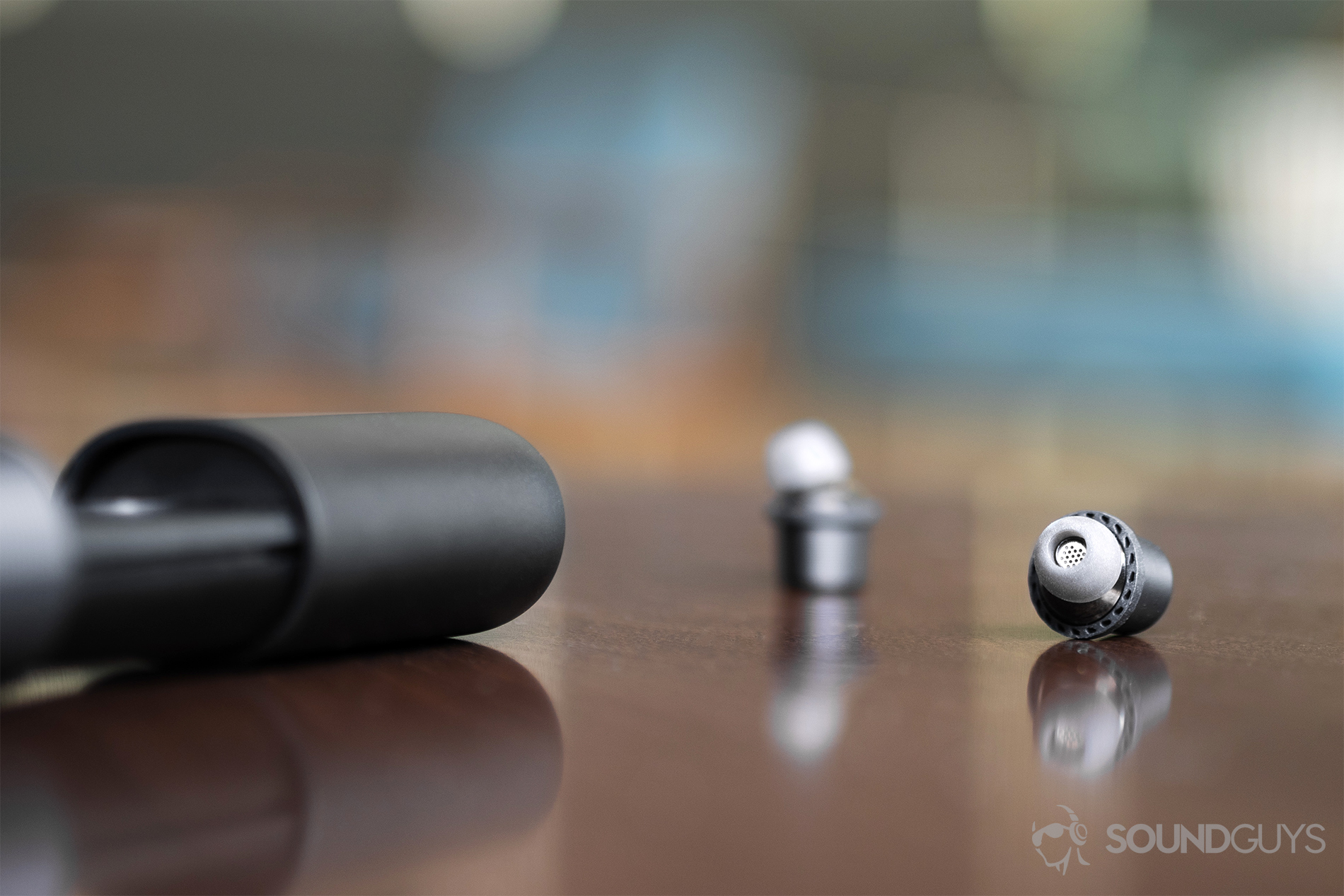 Rowkin Ascent Charge+ review: The earbuds on a wooden table with the charging case on middle-left of the image.