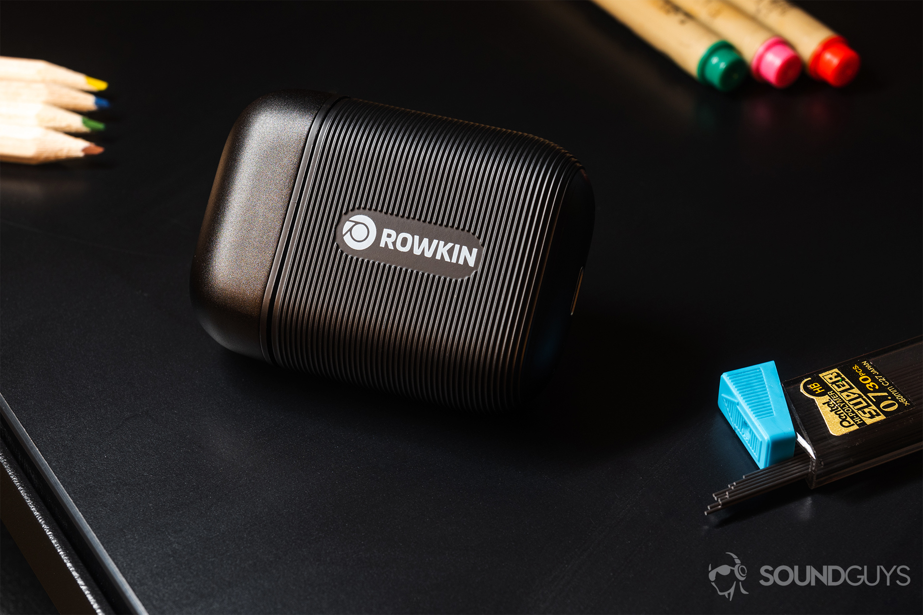 Rowkin Ascent Micro: The charging case with the Rowkin branding facing the lens. Pens, colored pencils, and lead are in the background.