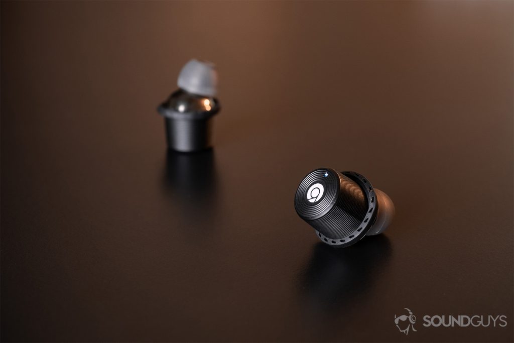 Rowkin Ascent Micro: One earbud with the touch panel facing the lens and the LED indicator lit up, while the other is faded into the background.