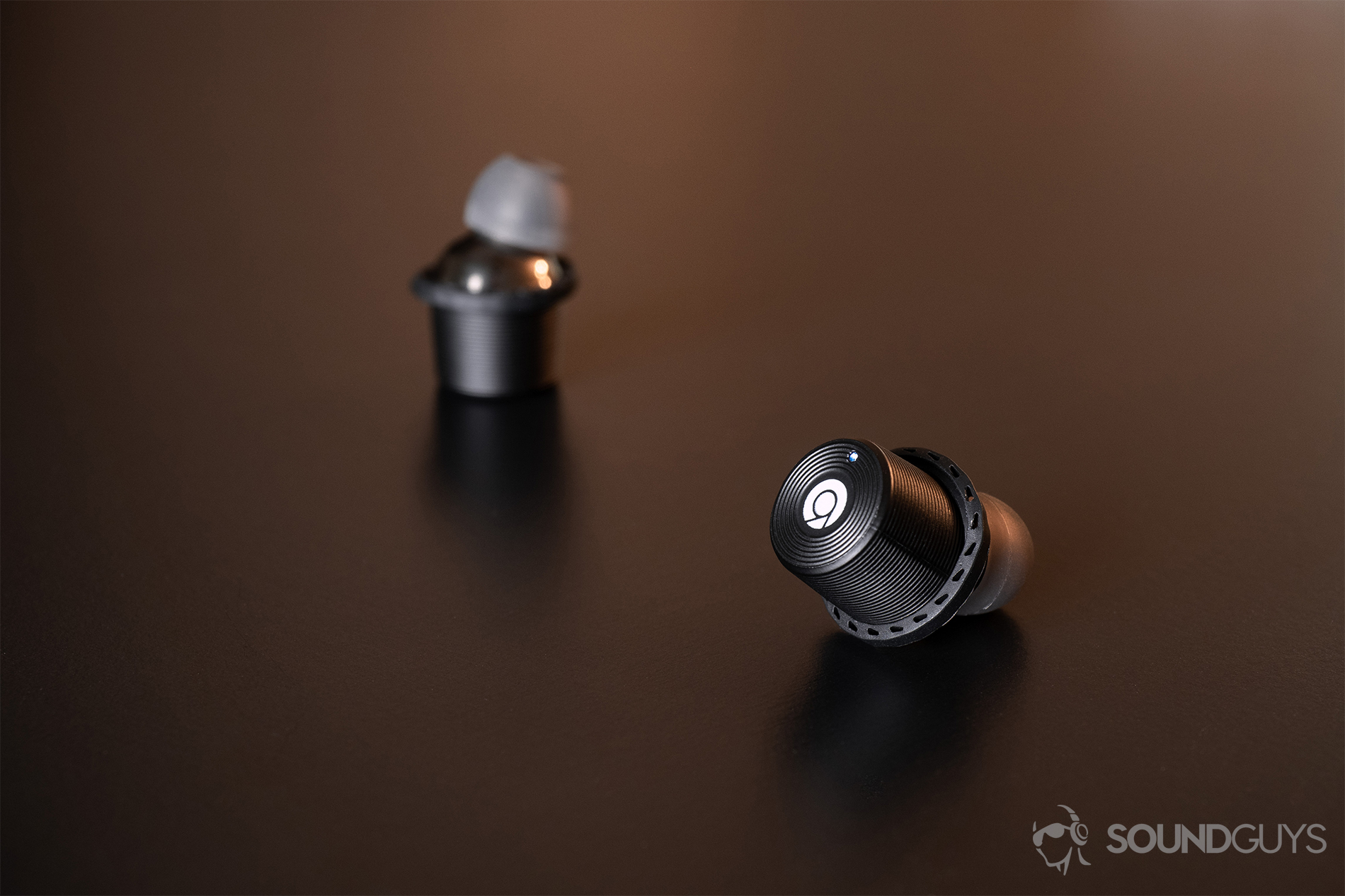 Rowkin Ascent Micro: One earbud with the touch panel facing the lens and the LED indicator lit up, while the other is faded into the background.