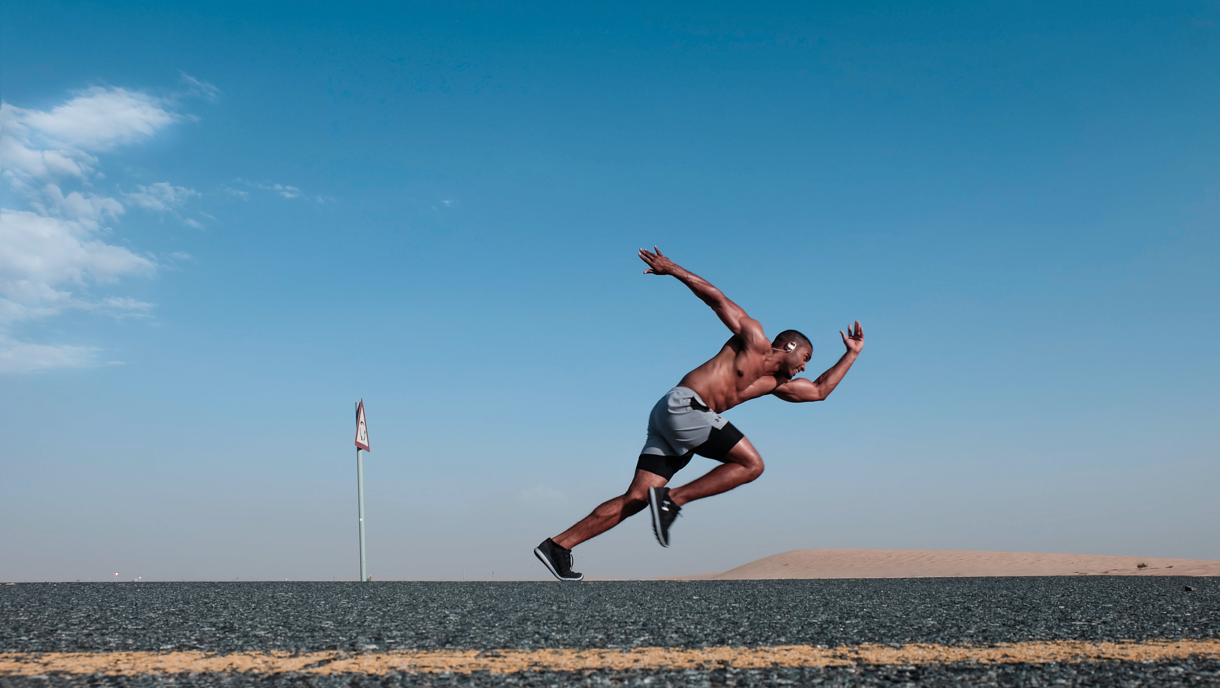 Pexel stock image of a running man who's outside in a desert with a bright blue, clear sky.