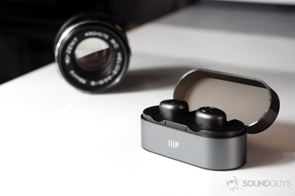 The earbuds in the case with a blurred out lens in the background.