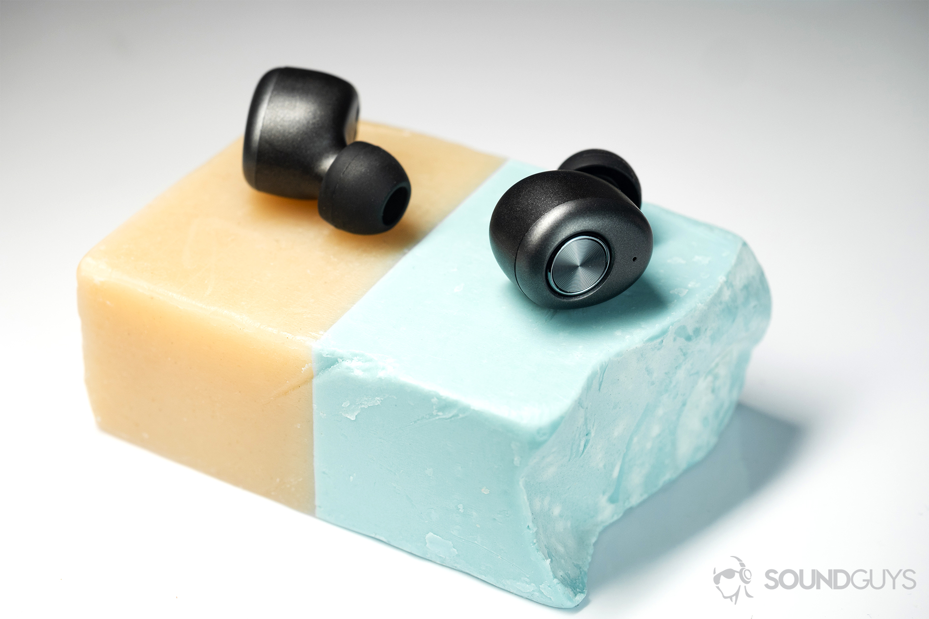 Monoprice True Wireless: Earbuds on a split-color bar of soap on a white surface.