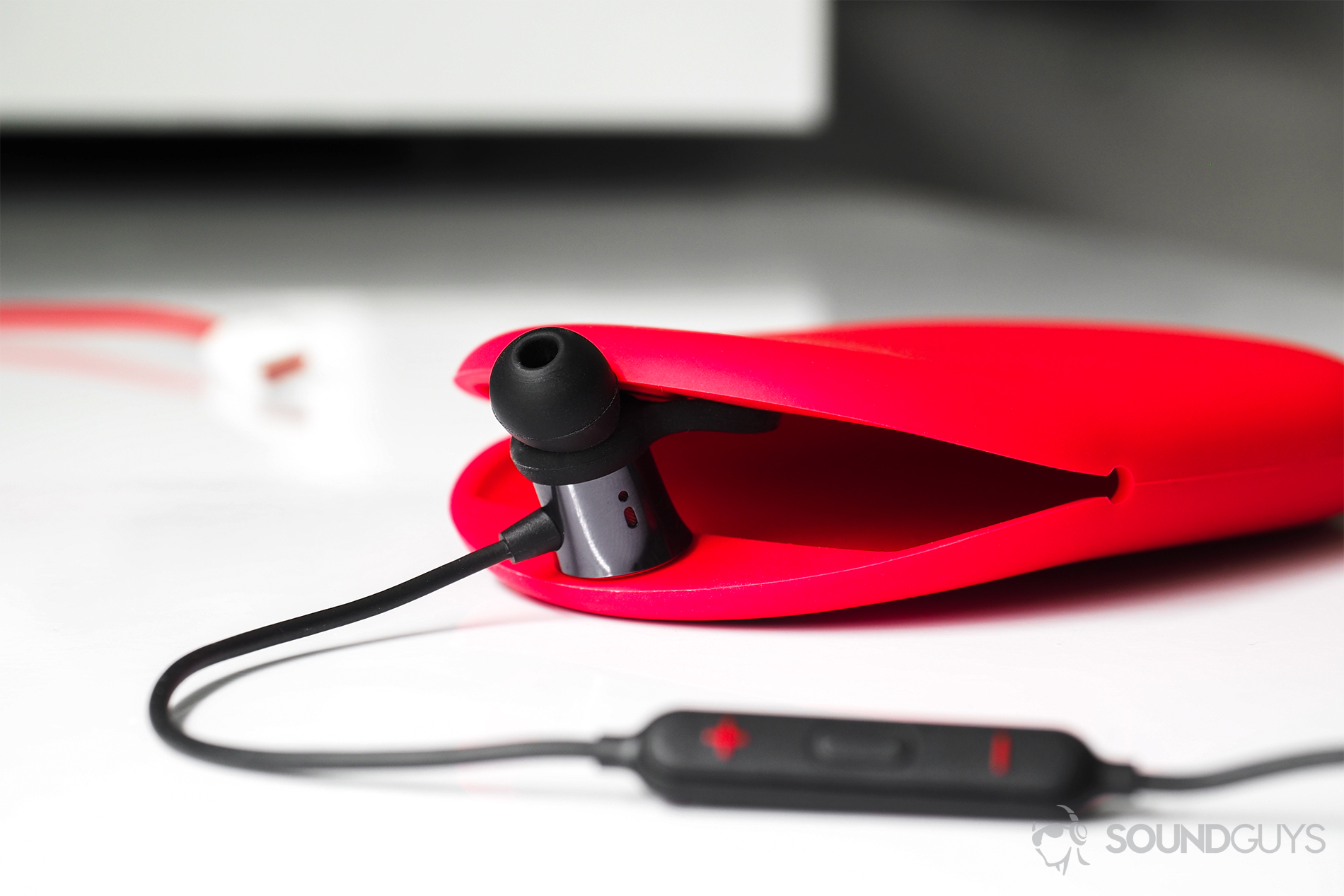 A straight-on image of the OnePlus Bullets Wireless earbuds with one of them holding the opening of the carrying case open.