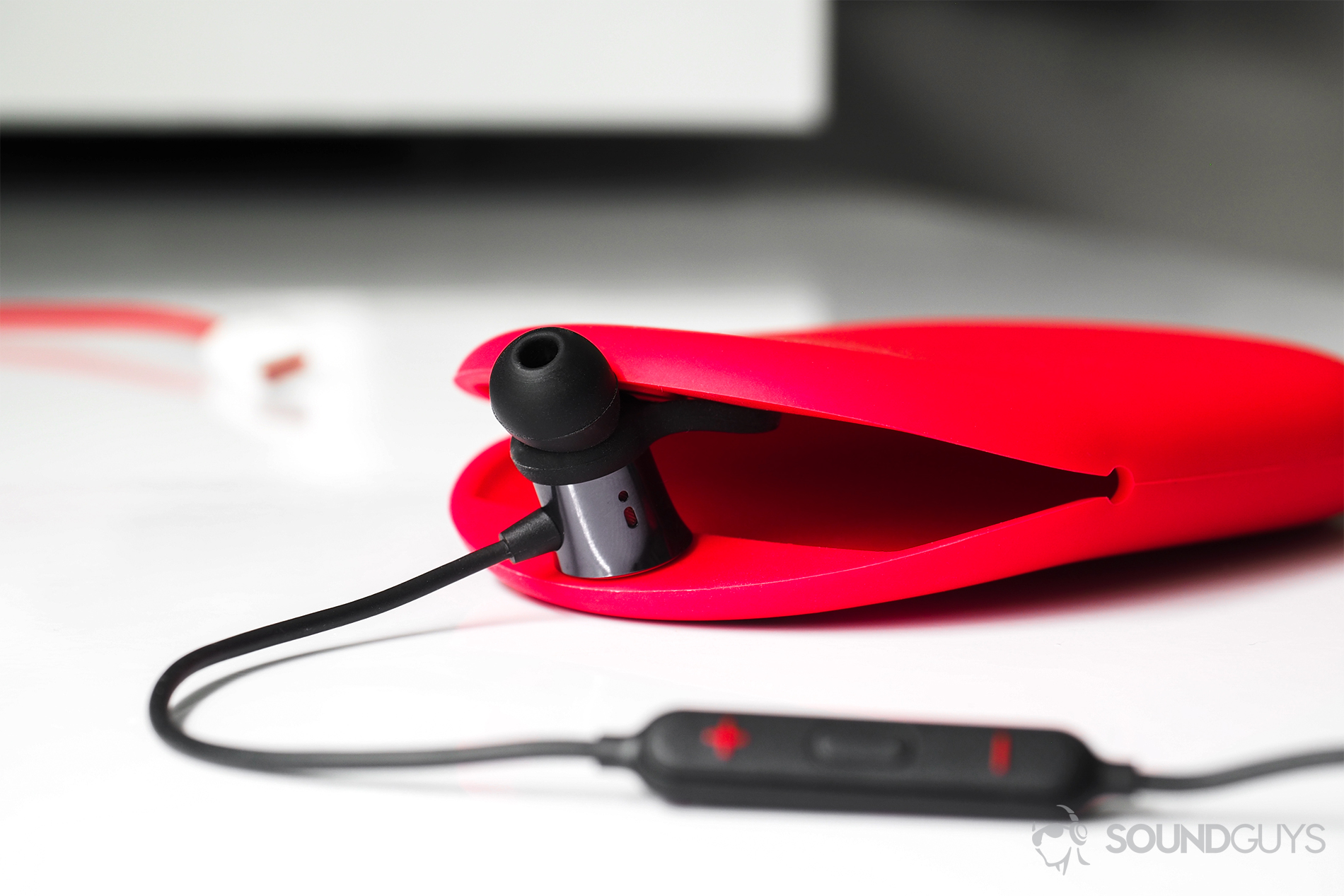 OnePlus_Bullets-3 A straight-on image of the OnePlus Bullets Wireless earbuds with one of them holding the opening of the carrying case open.