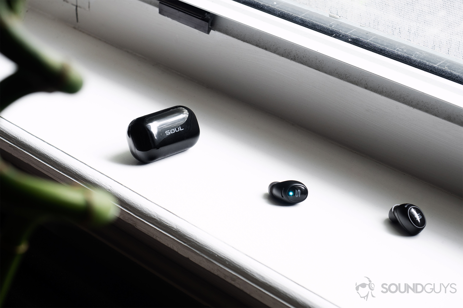 Soul Emotion: Earbuds laid in front of the charging case on a windowsill.