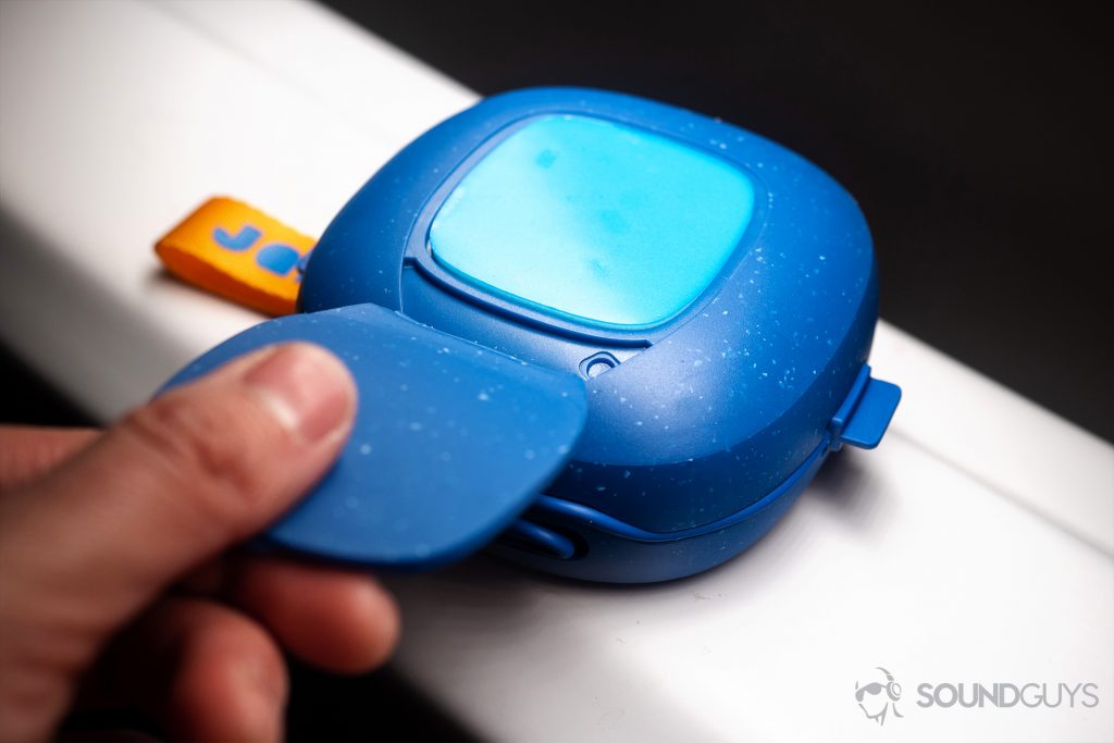 Jam Hang Up: A hand pulling back the flap to reveal the sticky pad on the back of the speaker.