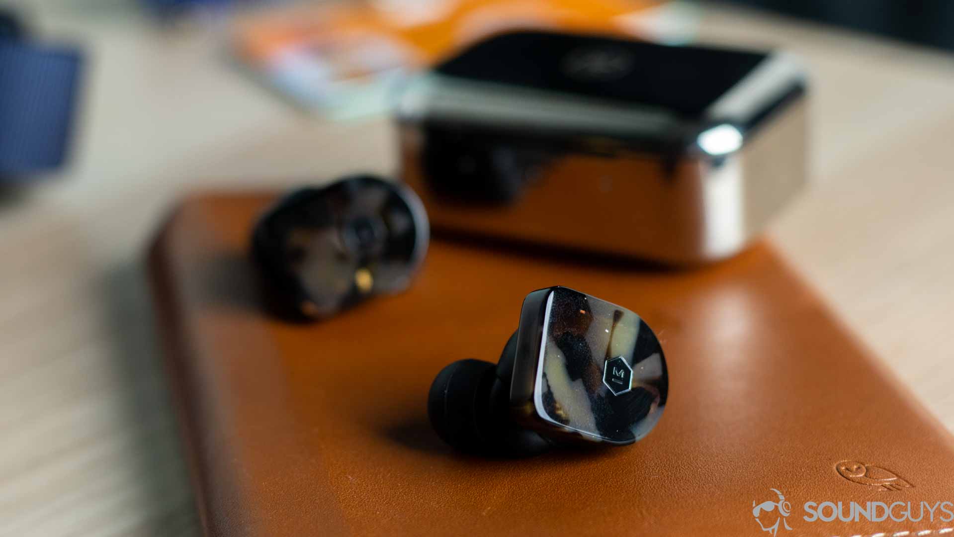 Close-up shot of the Master &amp; Dynamic logo on the MW07 earbuds.