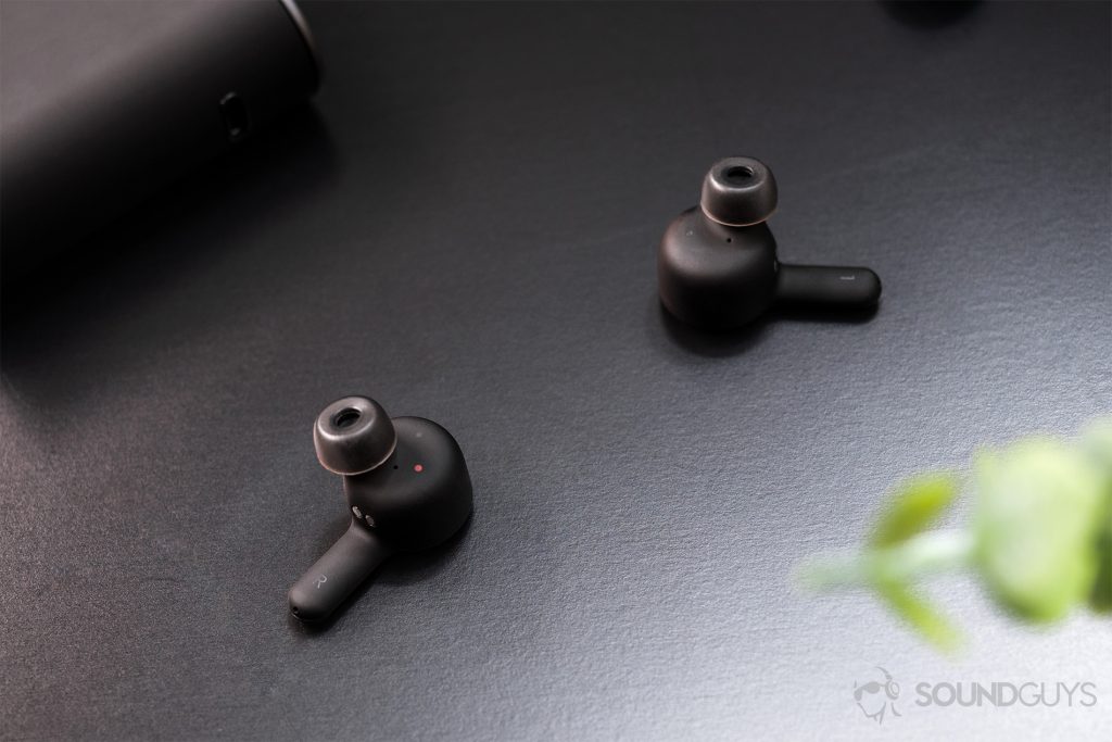 RHA TrueConnect: An image of the earbuds on a black surface with the charging case poking out from the top left corner.