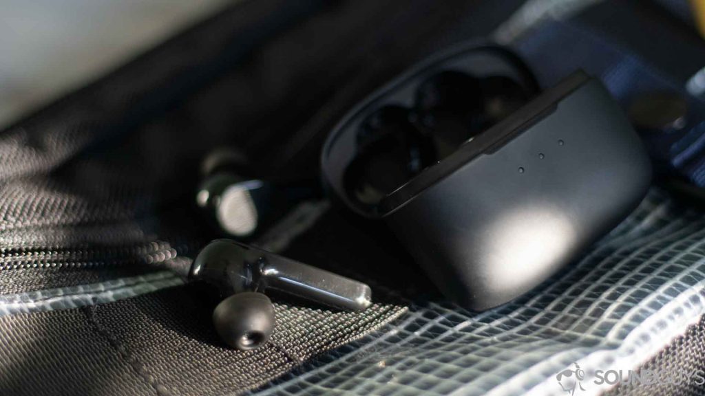 Pictured are the Anker earbuds next to the charging case on a sling pack.