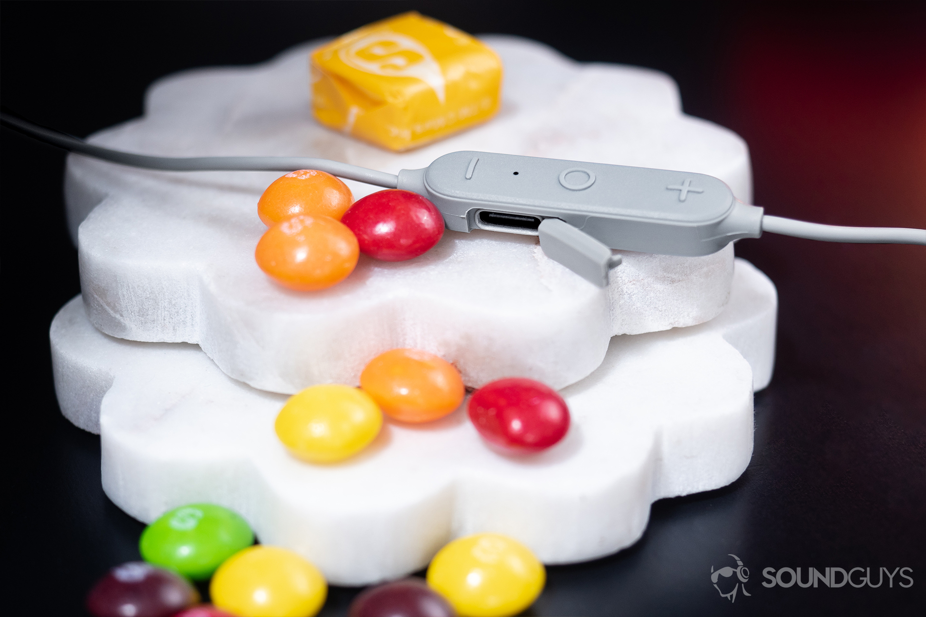 Aukey EP-B80: A close-up of the USB-C input with the module resting on unevenly stacked white coasters and Skittles layered atop.