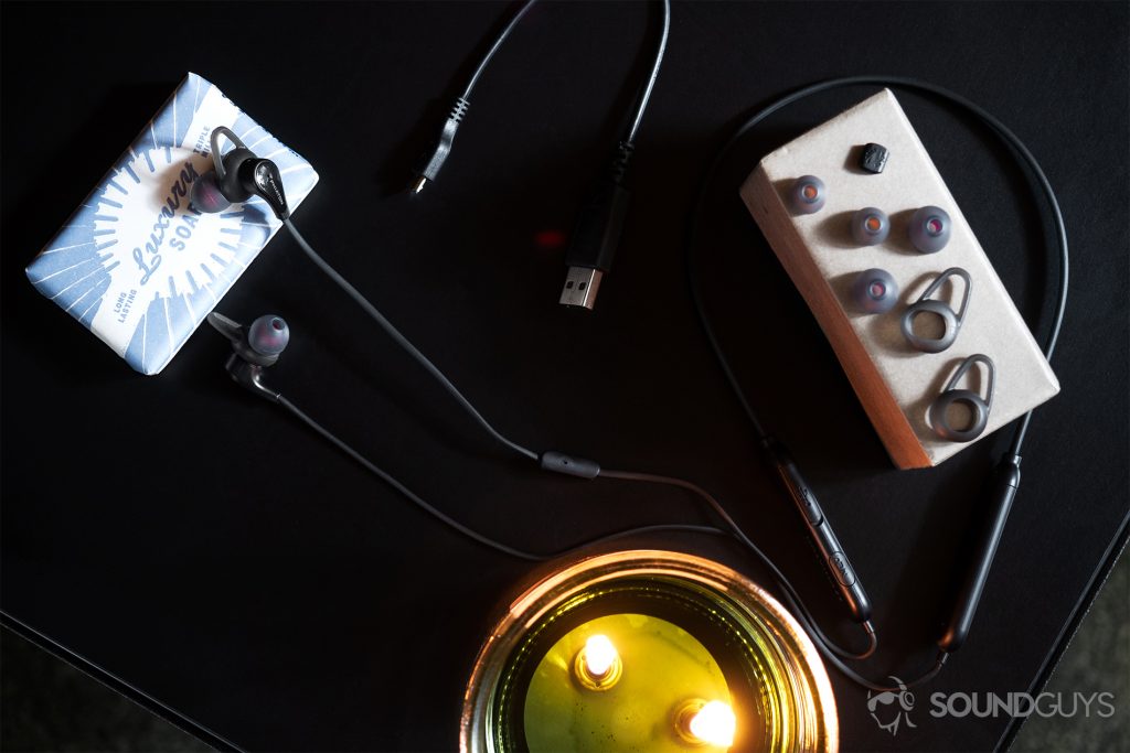 Phiaton Curve BT 120 NC: Top-down image of the the neckband earbuds with its accessories laid out including the extra ear and wing tips and micro-USB charging cable.