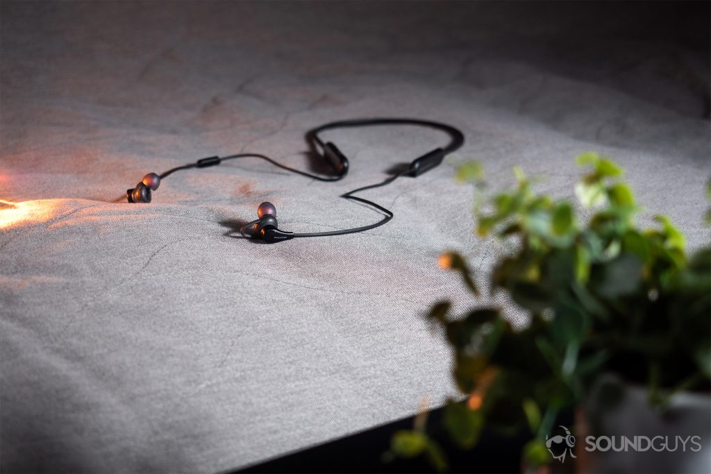 true wireless - Phiaton Curve BT 120 NC: An image of the neckband earbuds laying on a grey cloth surface with light leaking in from the left vertical frame.