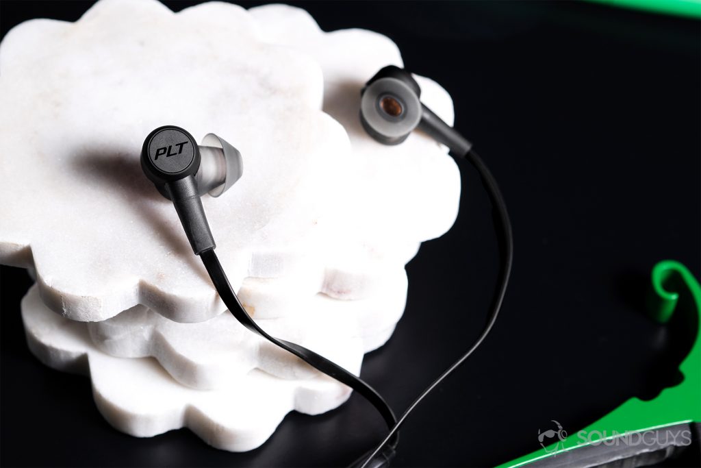 Plantronics BackBeat Go 410: The earbuds resting against white coasters stacked on top of each other on a black surface.