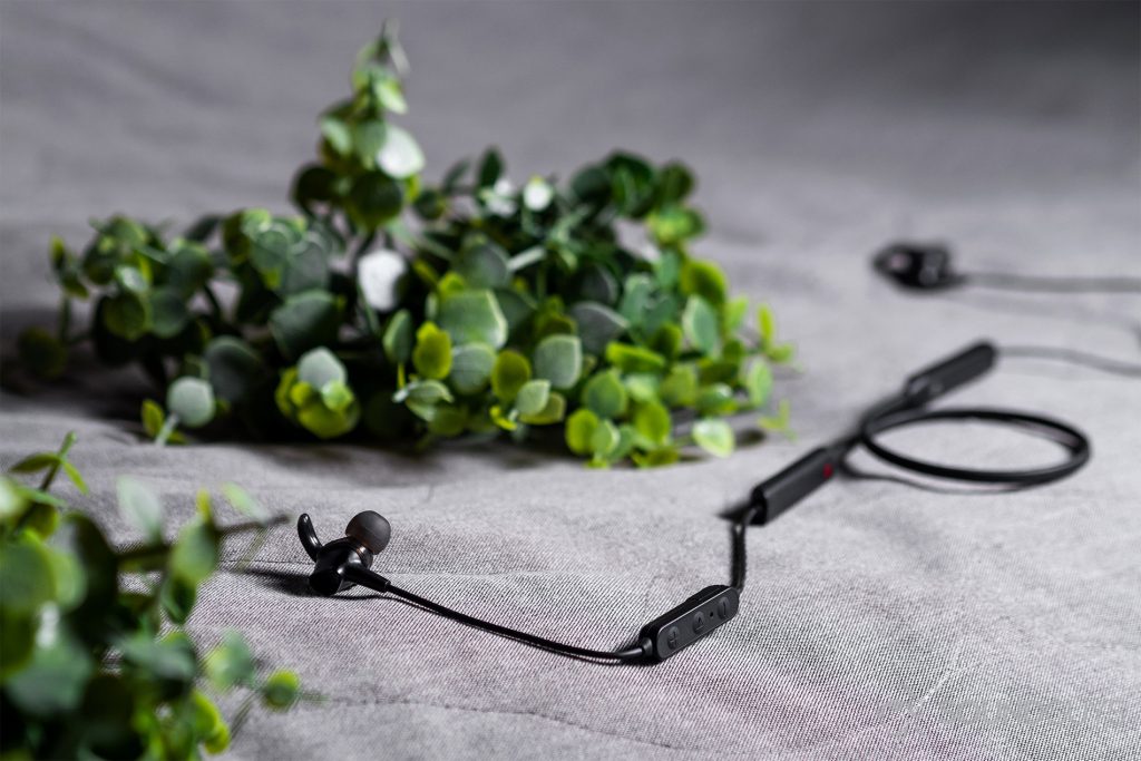 SoundPeats Engine: An image of the earbuds on a grey couch with artificial greenery.