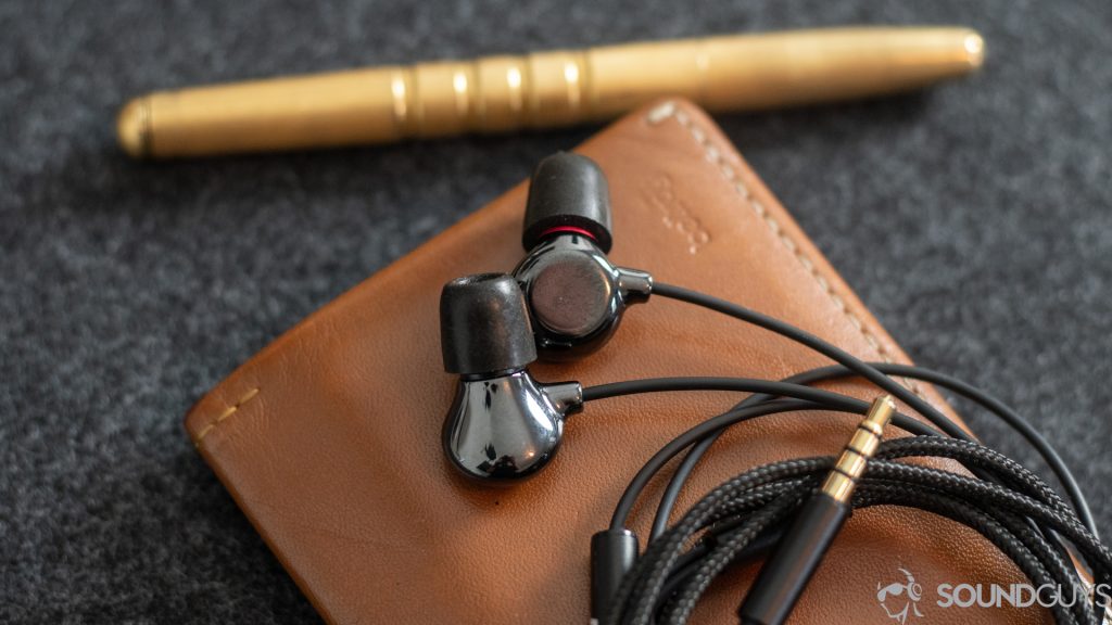 Pictured are the Elise earbuds on top of a wallet and pen. 