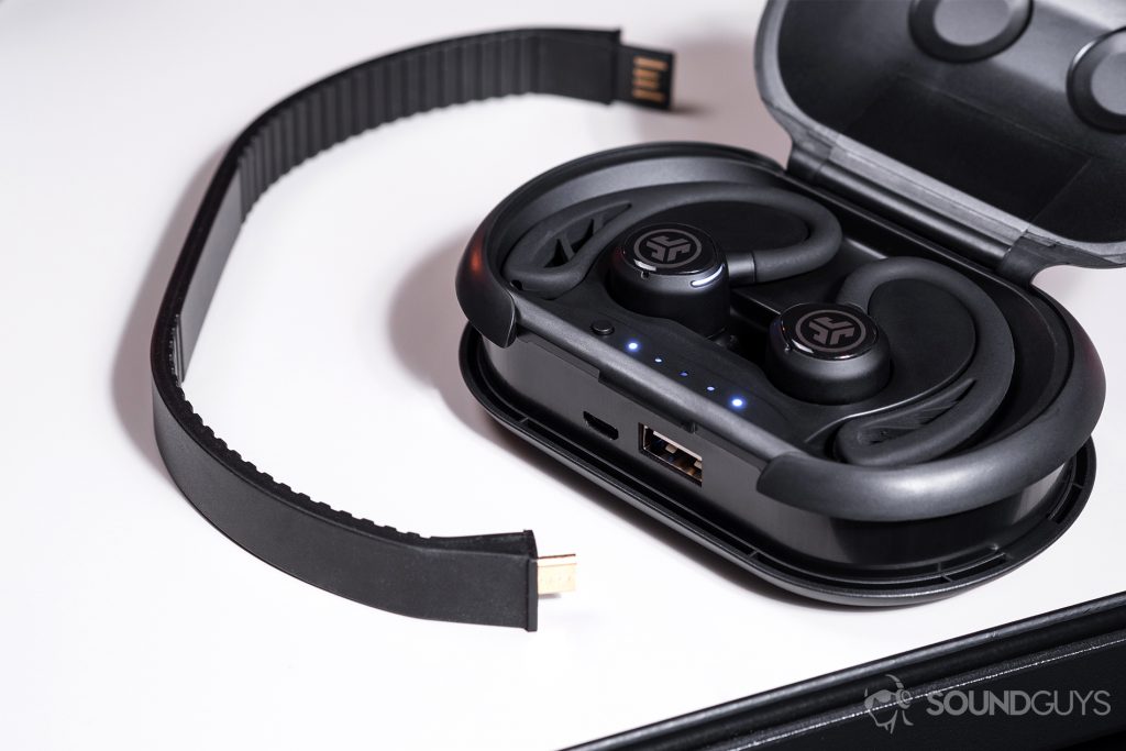 The case open with the earbuds placed inside. The removable micro-USB to USB-A cable is detached from the case on a white table.
