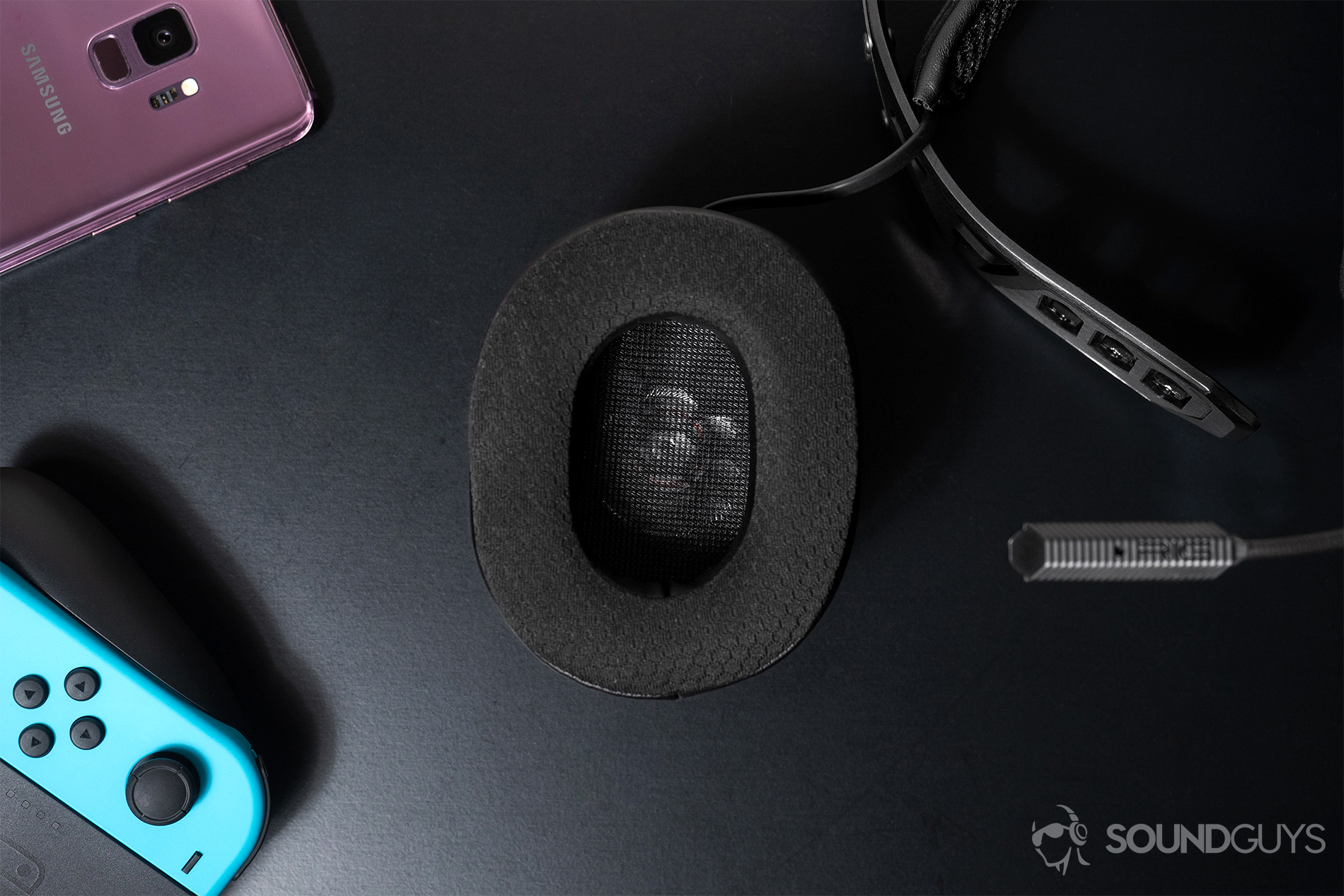 Top-down image of the detachable ear cup, both are detachable, with a Nintendo Switch in the bottom left corner and a Samsug S9 (lilac) in the top left corner of the image.