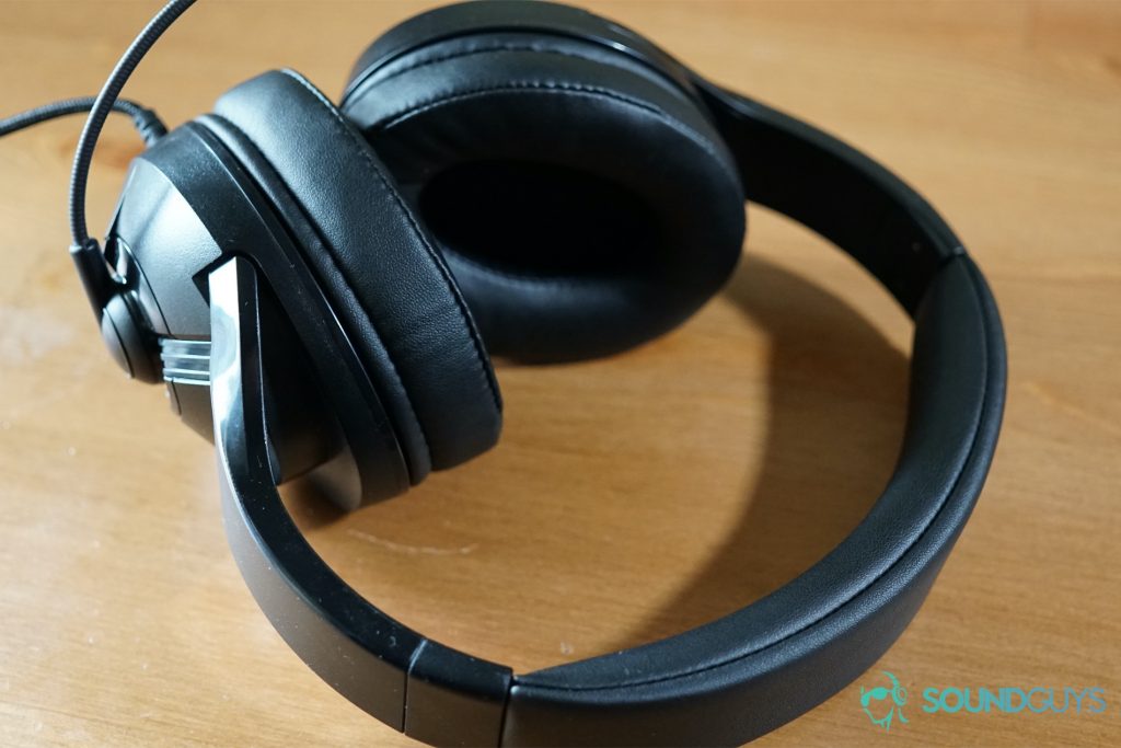 The AmazonBasics USB Gaming Headset sits on a wooden table, with its mic pointed forward.