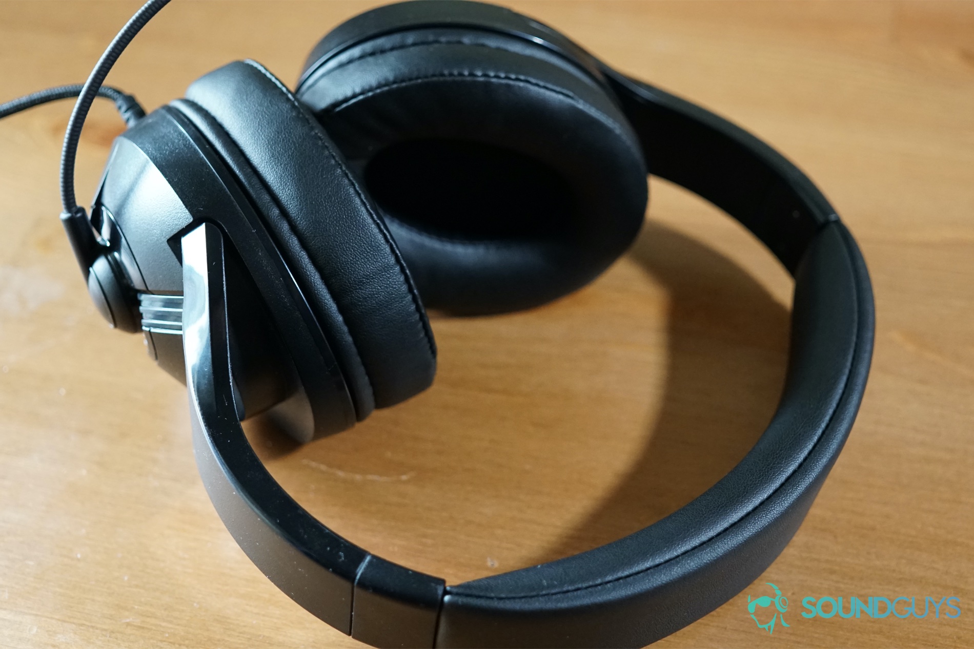The AmazonBasics USB Gaming Headset sits on a wooden table, with its mic pointed forward.