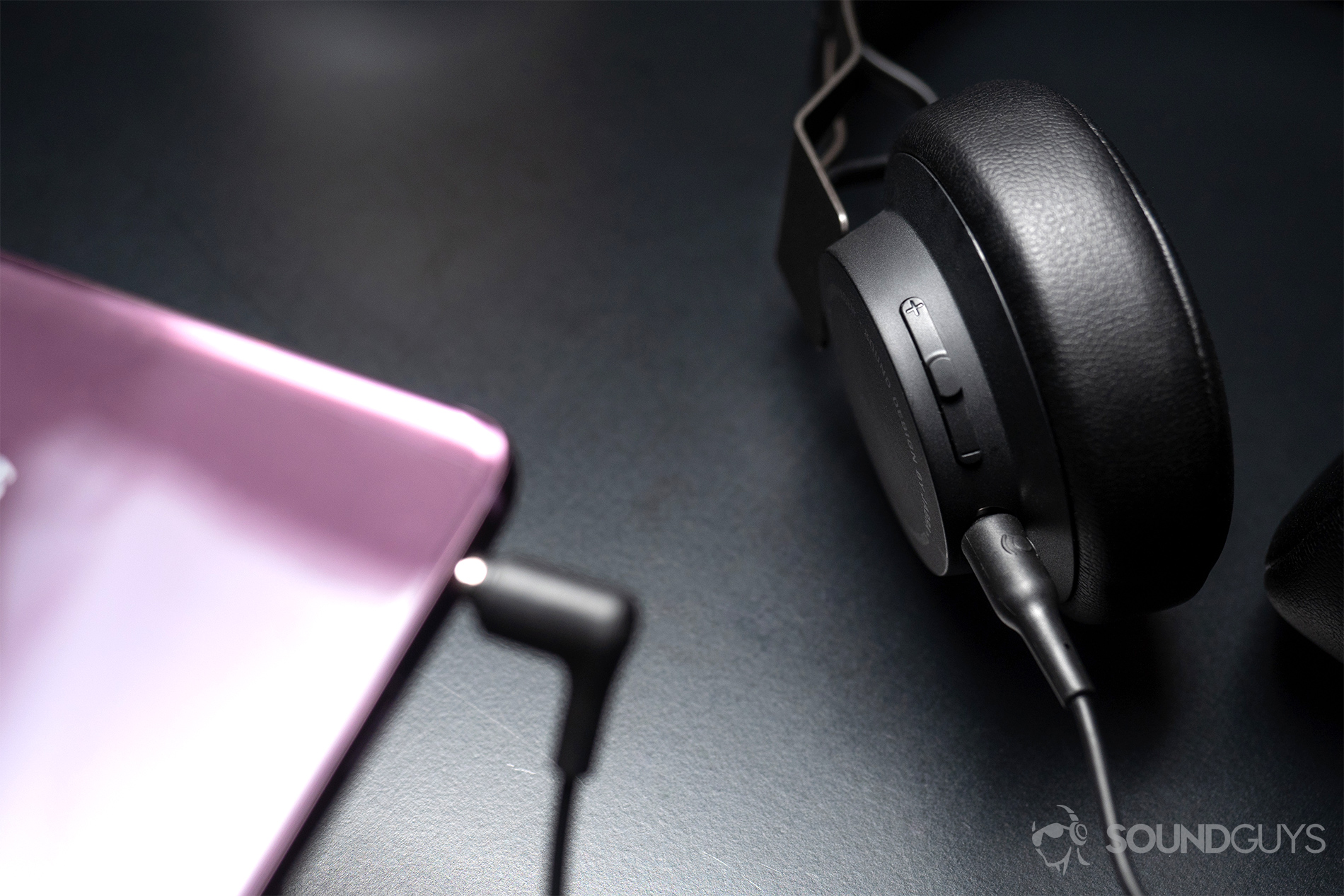A picture of the Jabra Move Wireless connected to the Samsung S9 in lilac with the headphone cable going from the phone to the headphones,. which are in the right side of the image.