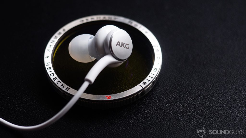 The AKG Samsung Galaxy S10e earbuds on a lens filter against a black background.