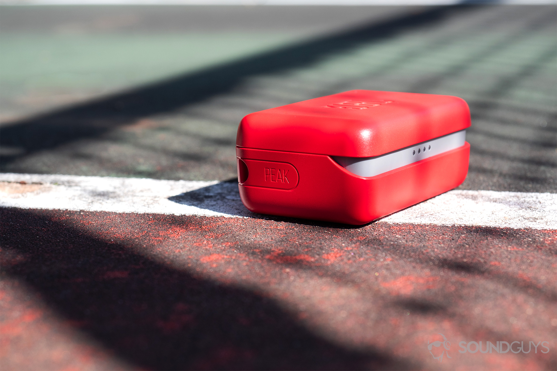 JBL Endurance Peak: The case angled away from the camera and resting on the boundary lines of a tennis court.