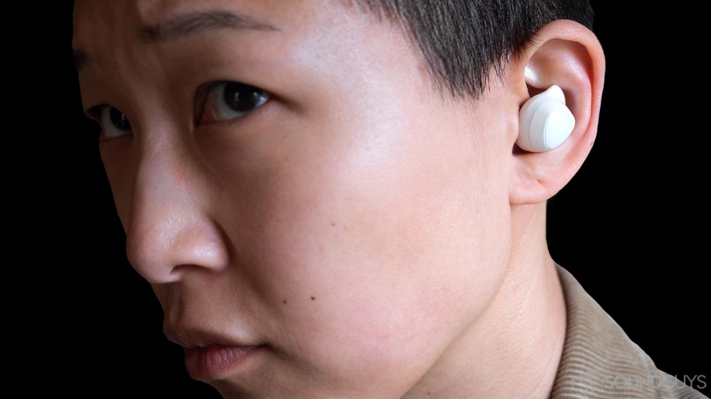 A picture of the Samsung Galaxy Buds earbuds being worn by a woman against a blacked out background.