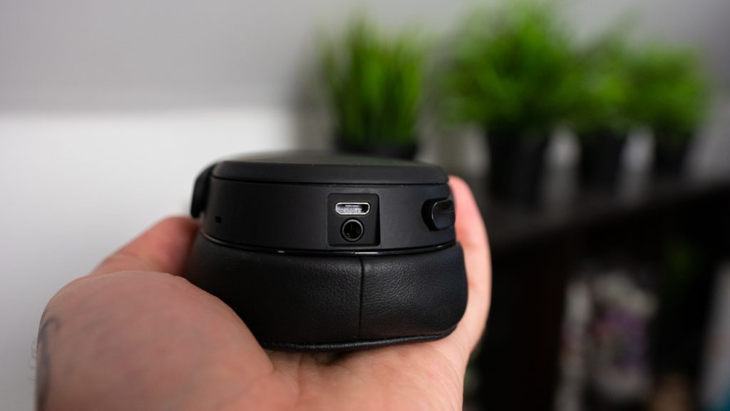 Man holding the Skullcandy Crusher Wireless with focus on micro-USB and 3.5mm inputs.