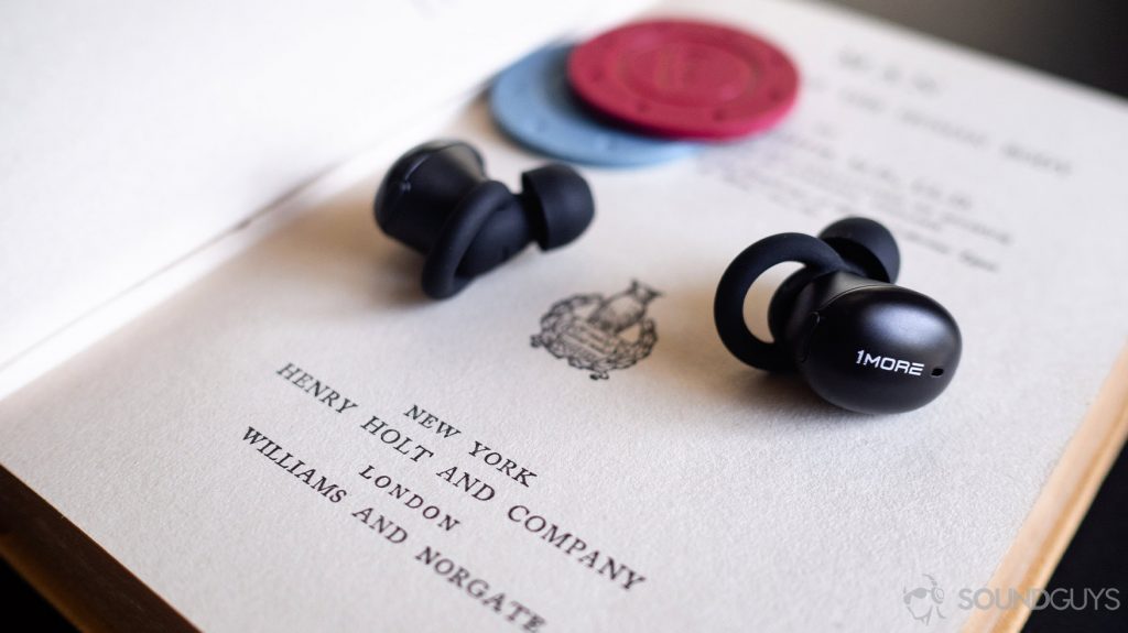 A photo of the 1More Stylish true wireless on an open book with blue and red poker chips in the background.