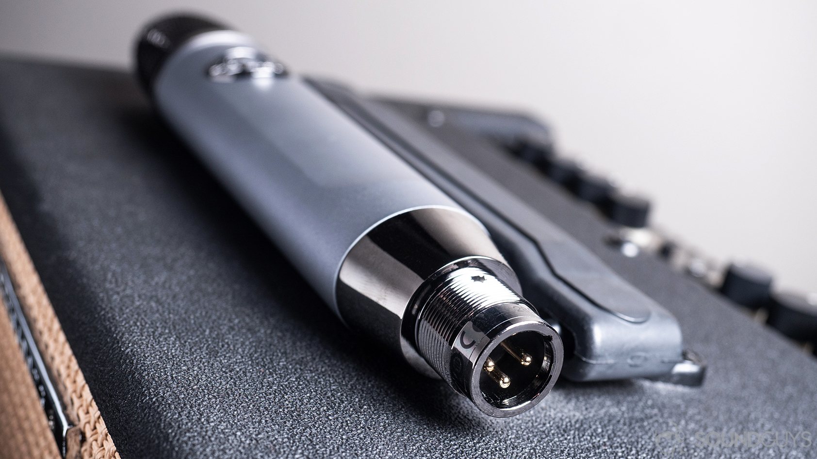 Blue Ember: The XLR input of the microphone, which is laying on a guitar amp.