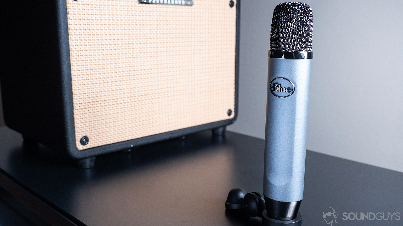 Blue Ember: The mic resting on a table in front of a guitar amp on a black surface.