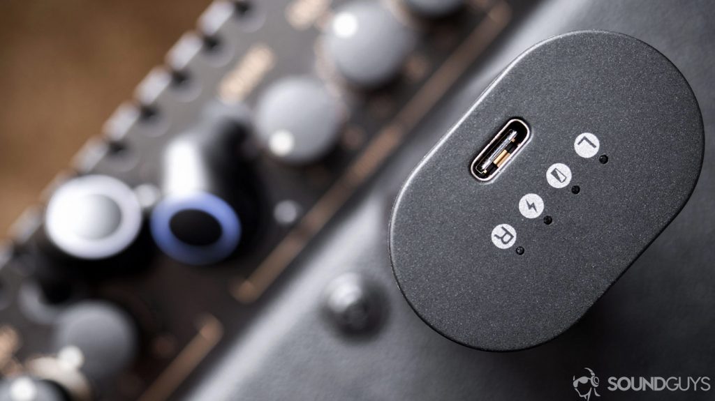 Top-down image of the Creative Outlier Air USB-C input on the charging case with the earbuds out of focus in the background.