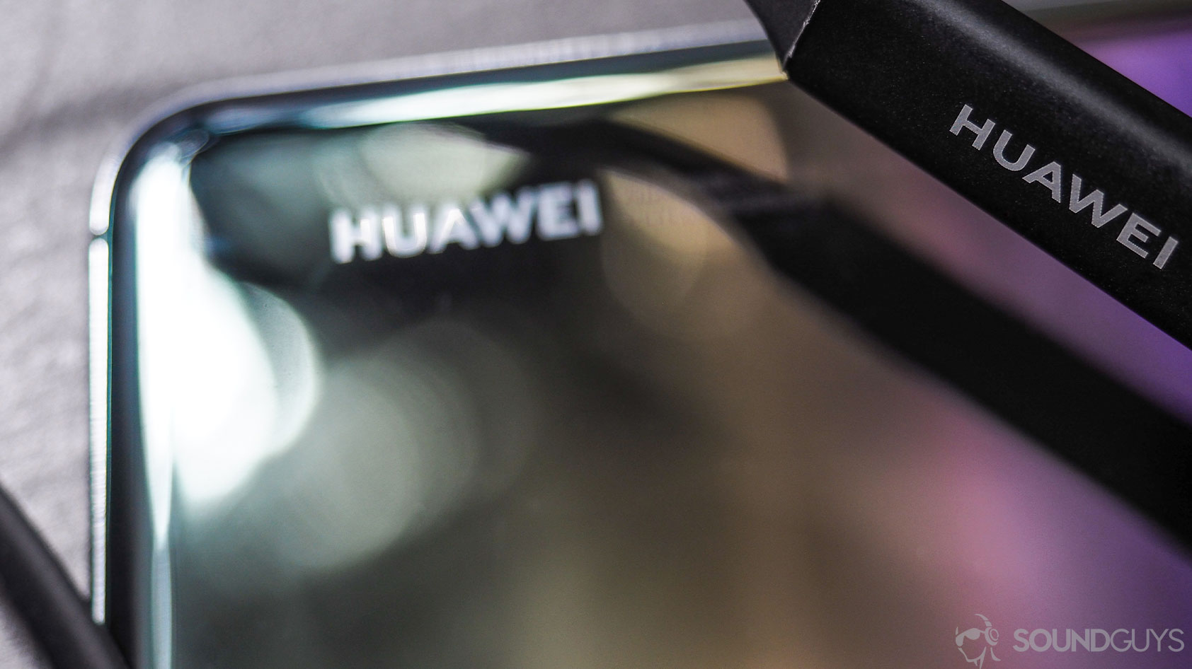 Huawei Freelace: Close-up of the Huawei logo on the phone and on the neckband of the FreeLace earbuds.