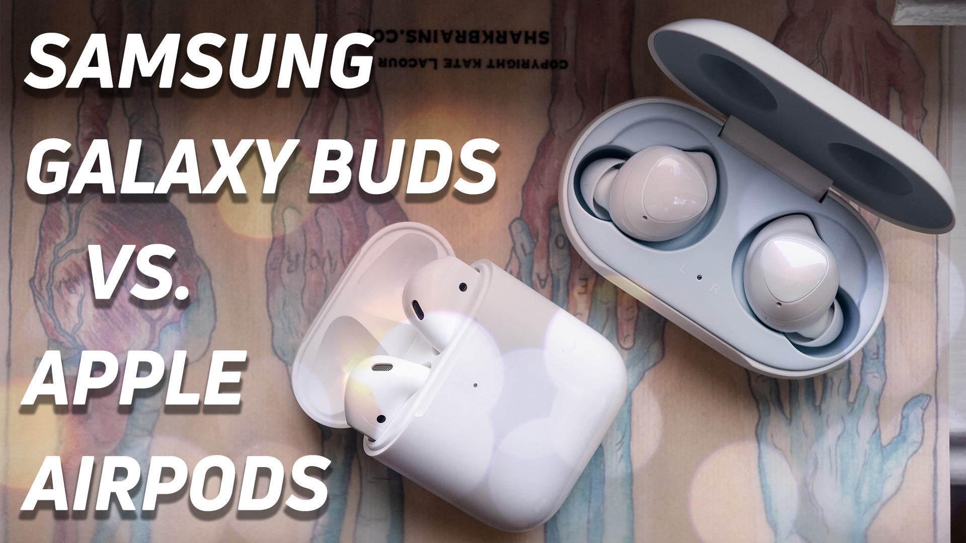 Samsung Galaxy Buds v Apple AirPods next to each other with charging cases open, top-down image.