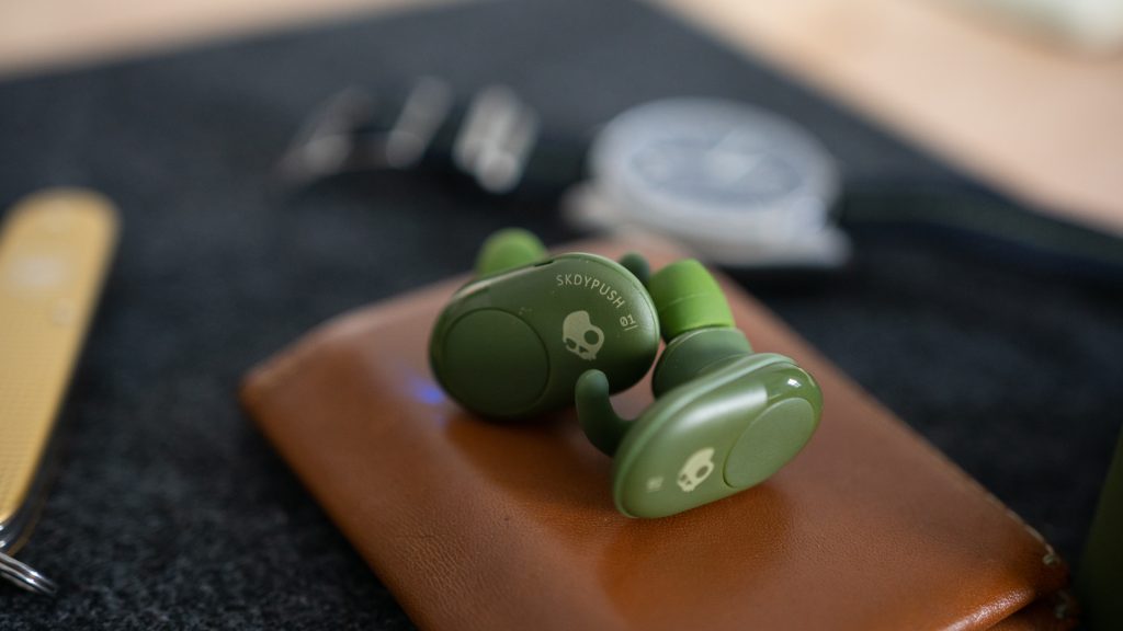 The Skullcandy Push true wireless earbuds next to each other on top of a wallet. 